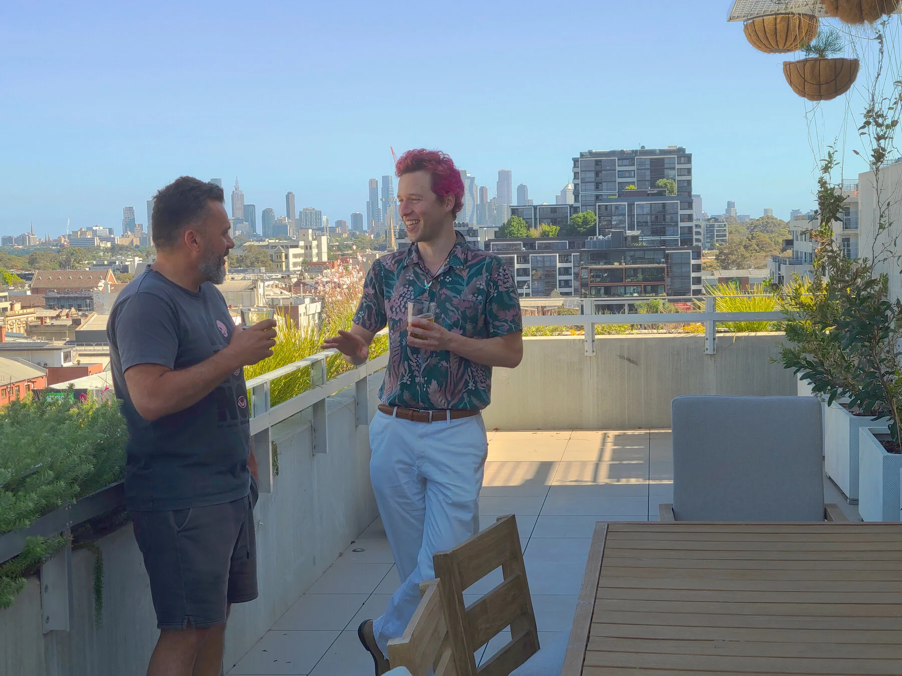 Friends enjoying drinks on the rooftop garden with Melbourne skyline behind